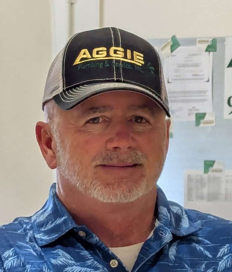 photo of the owner of aggie plumbing and service, smiling wearing an aggie hat